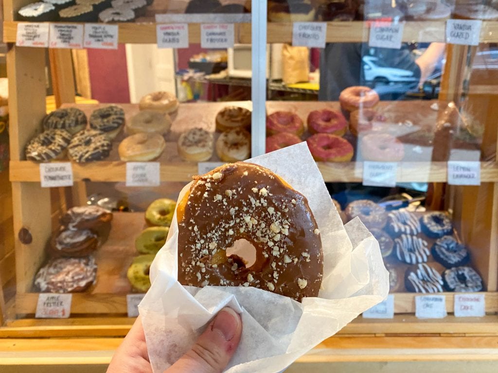 Rosquilla de boca grande sostenida frente a la caja de donas.